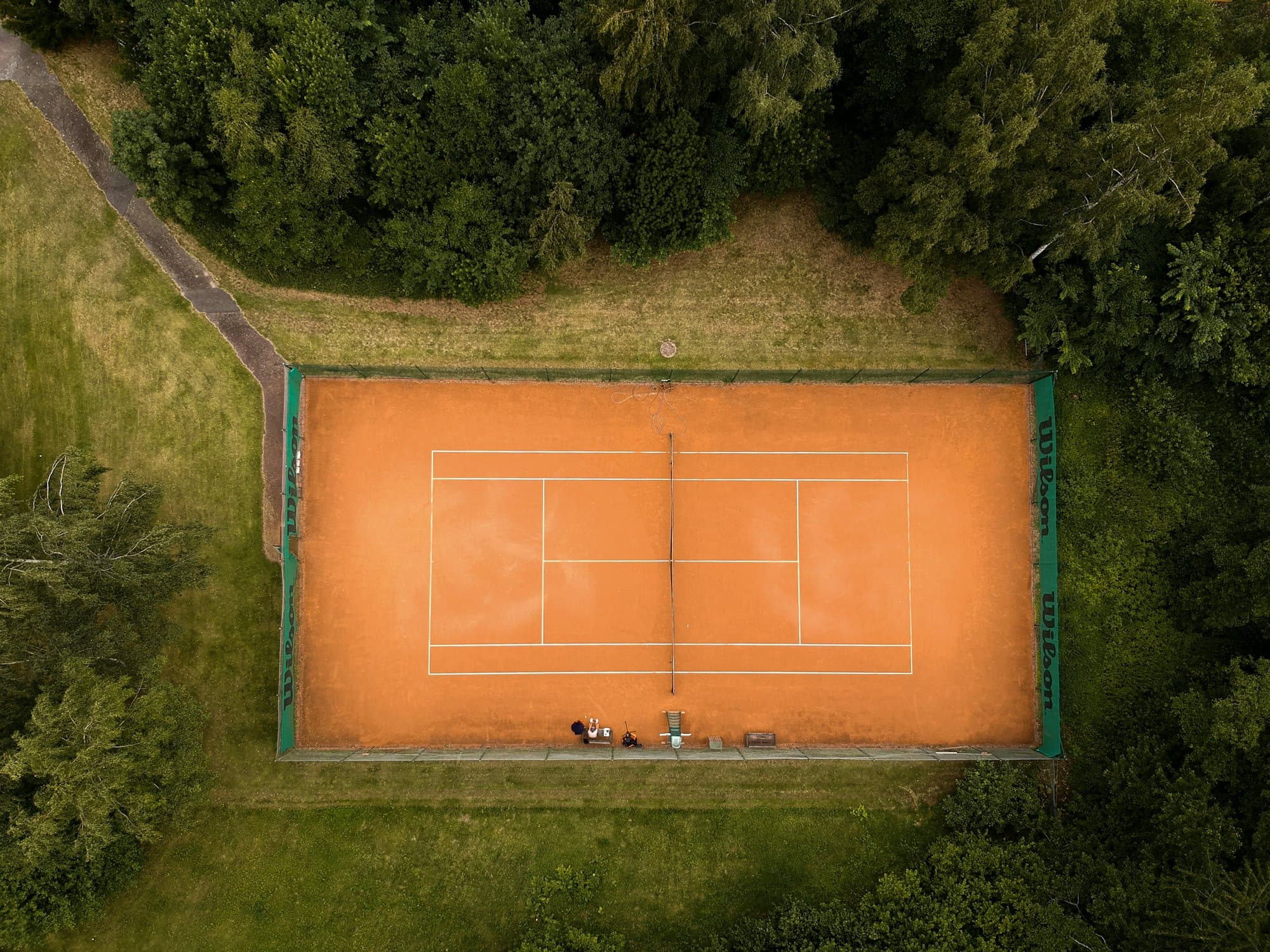 Aerial view of a clay tennis court framed by trees